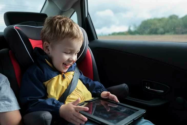 Фотография маленького мальчика, увлеченно смотрящего на экран планшета